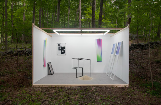 Fig. 12 The original installation placed in the middle of a forest composed of a cubicle made of three white walls (the fourth wall facing the audience is missing), a floor and some fluorescent lights as ceiling, inside six sculptures and paintings.