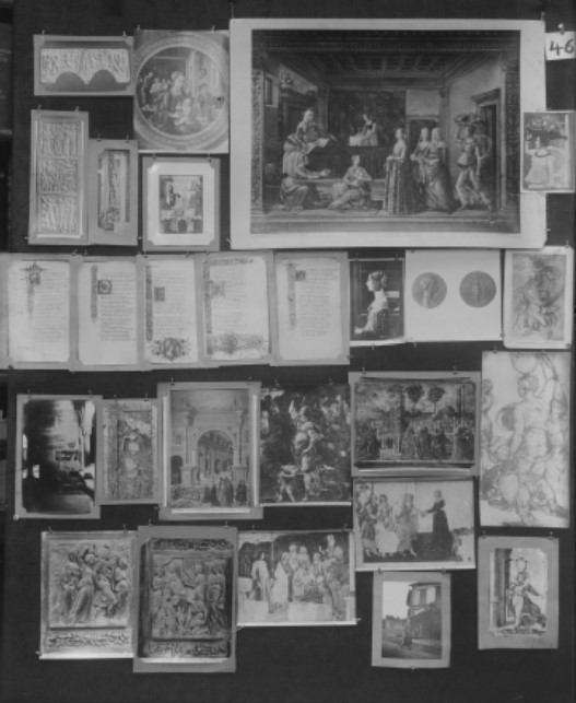 A vertical black and white photograph of a black surface covered by paper rectangular reproductions of book pages, paintings, drawings, sculptures and, with different sizes and formats, compiling images of female figures in various contexts (single portraits, body sketches, and group scenes both indoor and outdoor). At the right top corner of the image there is a paper tag with a numerical description: forty-six. 